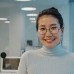 A smiling woman with glasses in an office.