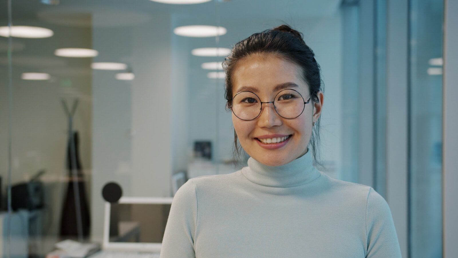 A smiling woman with glasses in an office.
